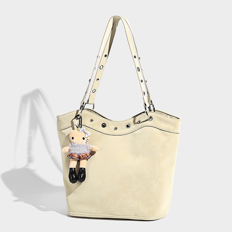 Große matte Tote-Bag in Lederoptik mit silberfarbenem Ösenbesatz, zwei Schulterriemen und abnehmbarem Plüschpuppen-Anhänger, Detailansicht