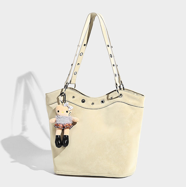 Große matte Tote-Bag in Lederoptik mit silberfarbenem Ösenbesatz, zwei Schulterriemen und abnehmbarem Plüschpuppen-Anhänger, Detailansicht