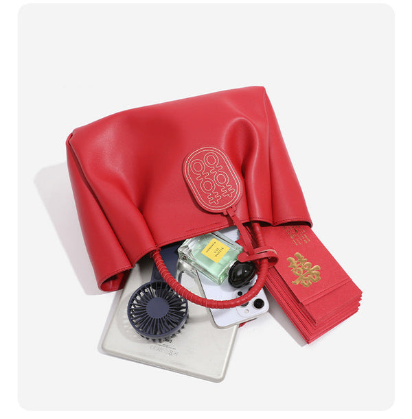 Strukturierte Tote-Bag in mattem Rot mit gedrehten, umwickelten Tragegriffen, Anhänger mit Doppelglücks-Symbol und herausnehmbarem grauem Innenfach mit Reißverschluss