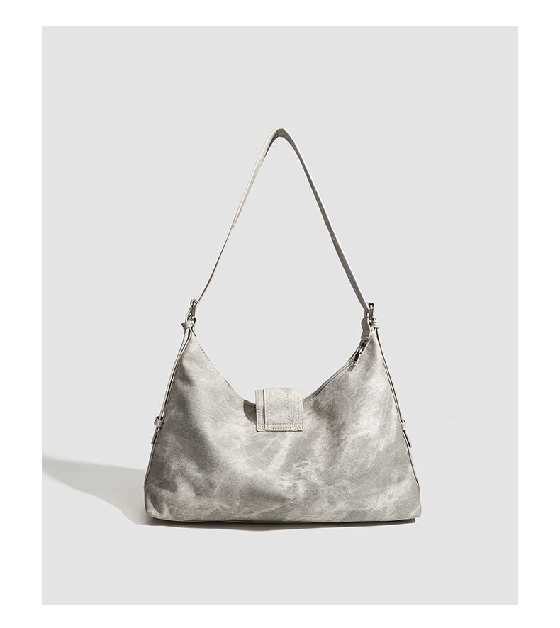 Slouchy trapezoid hobo shoulder bag with distressed textured finish, silver rivet corner accents, centre buckle strap, and