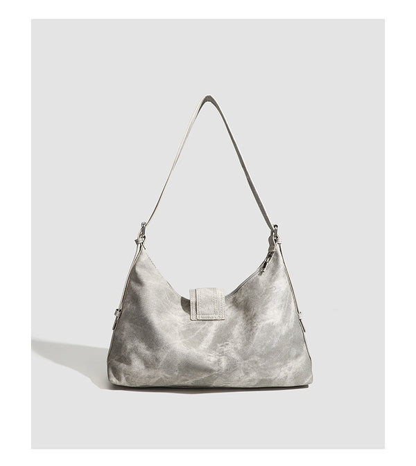Slouchy trapezoid hobo shoulder bag with distressed textured finish, silver rivet corner accents, centre buckle strap, and