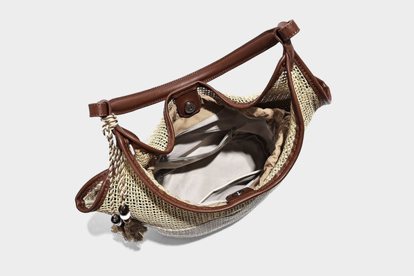 Two-tone beige and cream woven straw hobo shoulder bag with brown leather-look trim, long shoulder strap, and tassel-bead