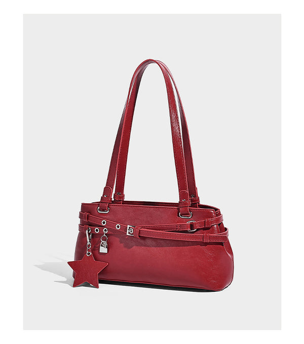 Structured glossy leather-look shoulder bag with wraparound belt straps, silver-tone hardware, and dangling star charm
