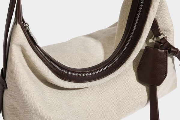 Lässige Hobo-Schultertasche aus haferfarbenem Canvas mit dunkelbraunen Besätzen in Lederoptik, silberfarbenem Reißverschluss und langem, verstellbarem