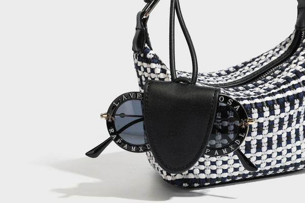 Small crescent shoulder bag in black-and-white woven textile with smooth black leather-look trim, zip-top closure, knotted