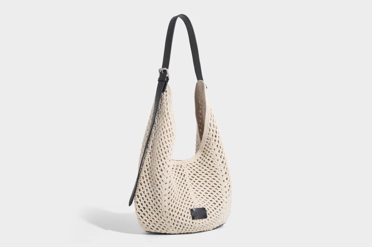 Cream openwork crochet hobo bag with black leather-look strap and trim patch accent, slouchy teardrop silhouette, detail view