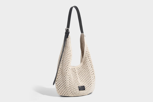 Cream openwork crochet hobo bag with black leather-look strap and trim patch accent, slouchy teardrop silhouette, detail view