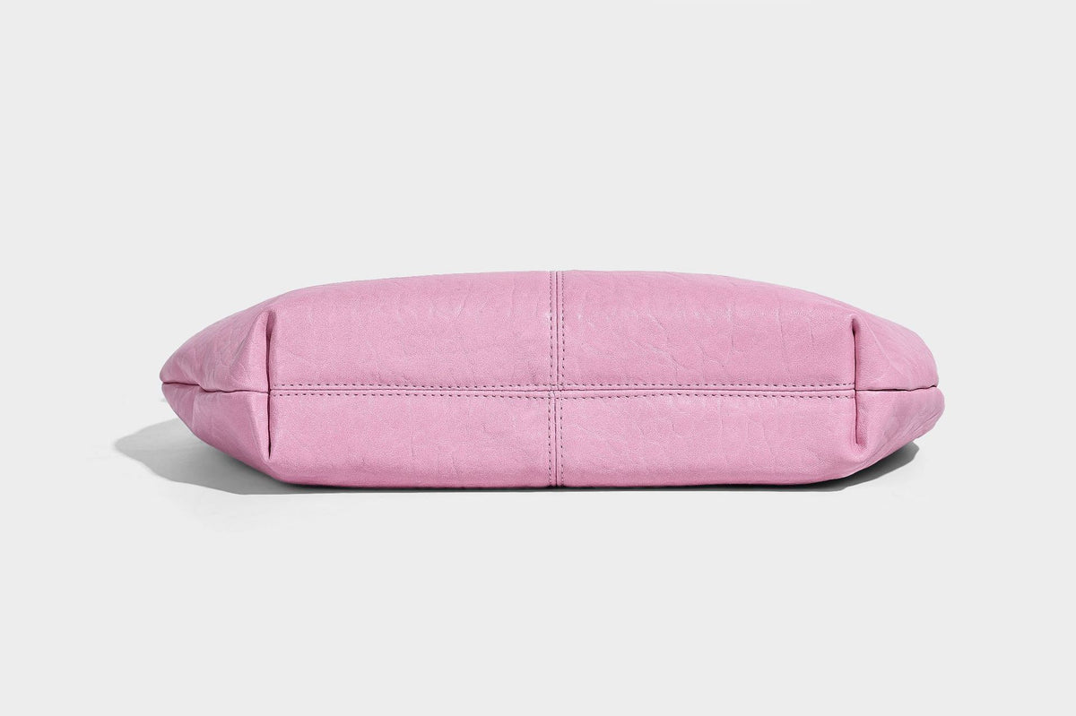 Slouchy crescent half-moon shoulder bag in pink pebbled textured finish with floral charm and knotted side detail, detail