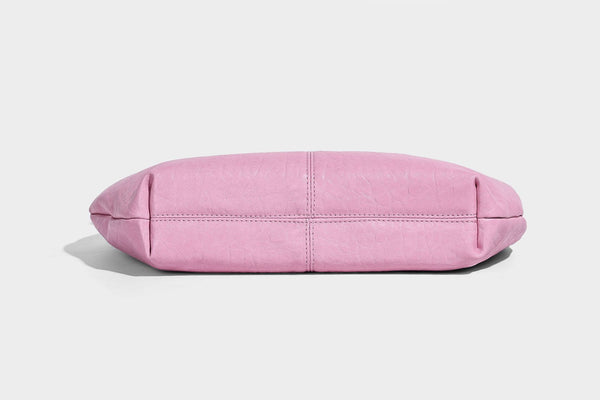 Slouchy crescent half-moon shoulder bag in pink pebbled textured finish with floral charm and knotted side detail, detail