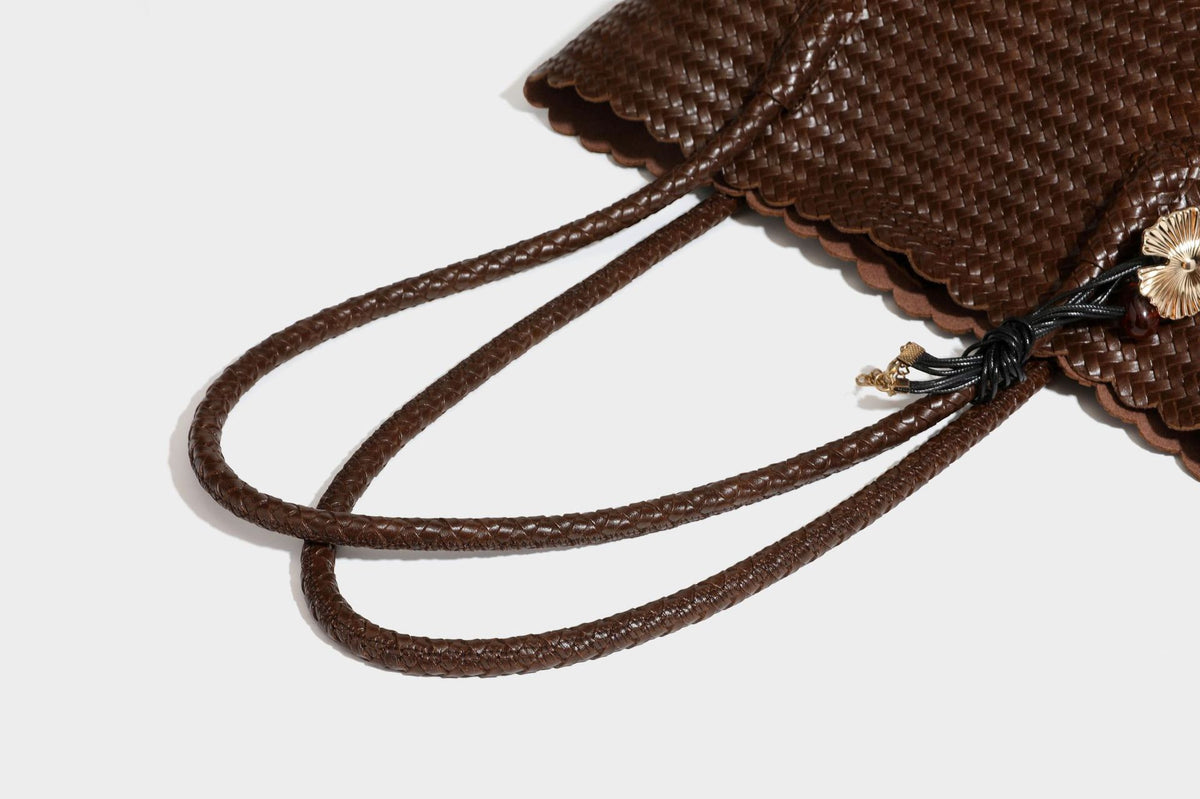 Large open-top woven leather-look tote bag in dark brown with scalloped edge, braided double shoulder straps, and decorative