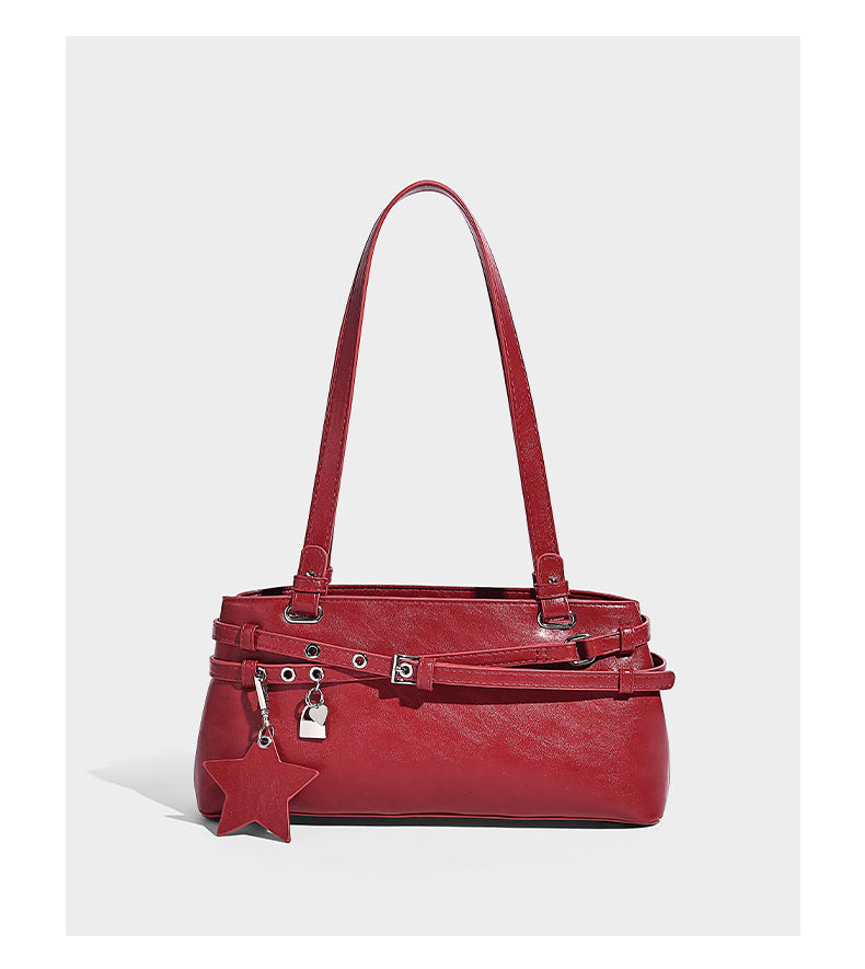 Structured glossy leather-look shoulder bag with wraparound belt straps, silver-tone hardware, and dangling star charm