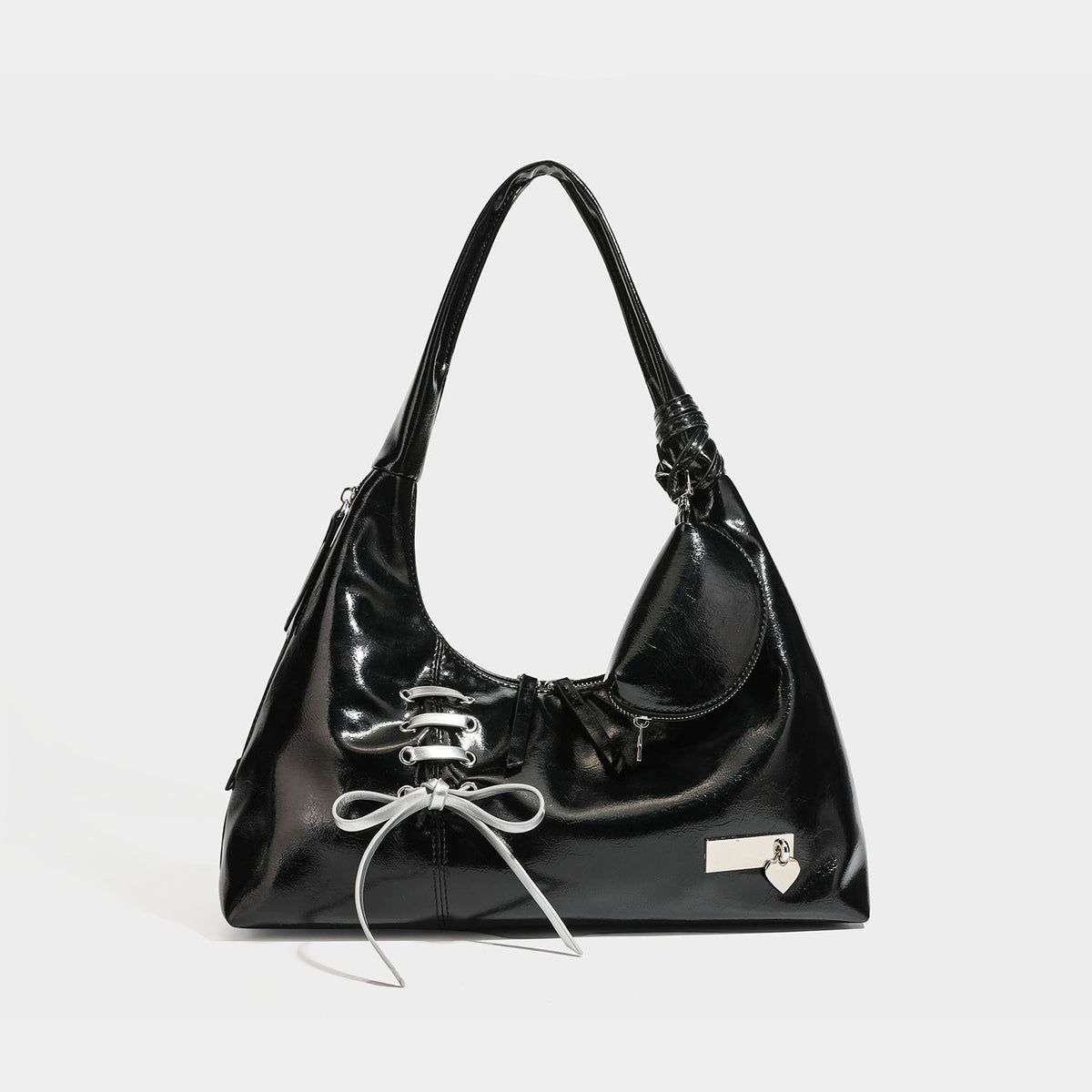 Weich fallende Hobo-Schultertasche mit glänzender Oberfläche in Lederoptik, silberfarbenen Schnürringösen und Schleife aus Ripsband auf der Vorderseite, Detail