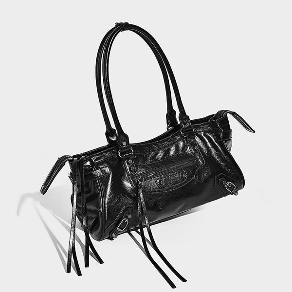 Längliche Schultertasche in Zylinderform mit glänzender Lederoptik, silberfarbenen Nieten, seitlichen Quasten und mehreren Außenreißverschlüssen