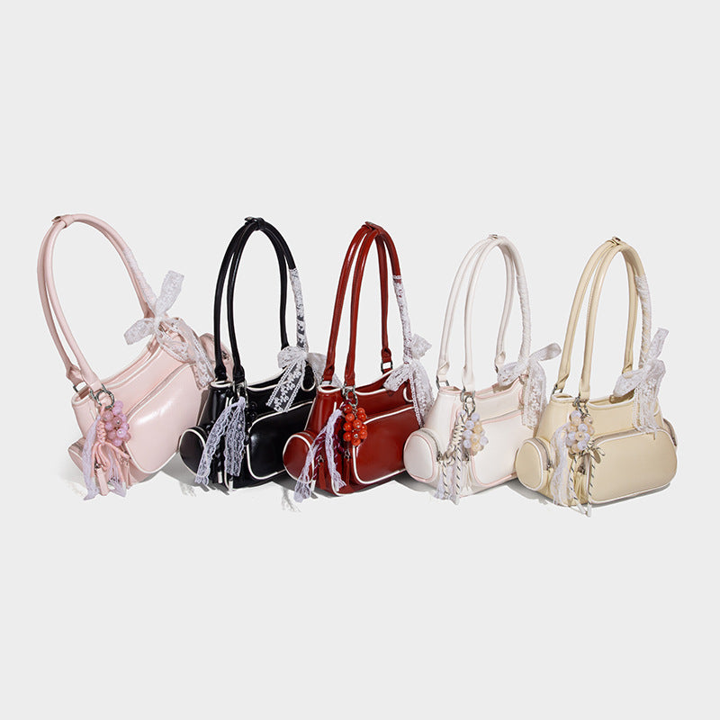 Small structured glossy shoulder bag with white piping trim, lace bow and red bead charm, zip side pockets, and silver-tone
