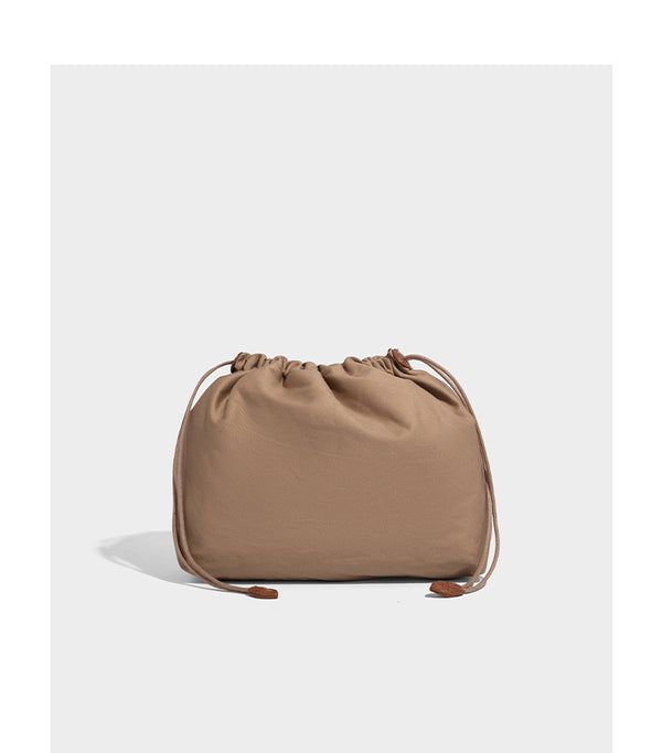 Structured woven-texture tote bag with brown braided top handles, decorative tassel charm, and detachable shoulder strap