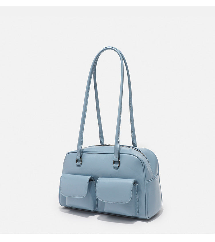 Structured glossy leather-look bowling shoulder bag with two front flap pockets, top zip closure, and long double shoulder