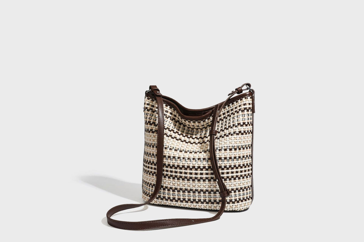 Woven stripe bucket shoulder bag in cream and dark brown with leather-look trim, knotted adjustable strap, and small shield