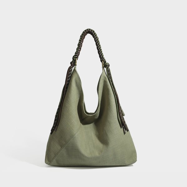 Soft slouchy cream canvas shoulder tote with braided brown and green cord handle, gold-tone ring hardware, and tassel trim