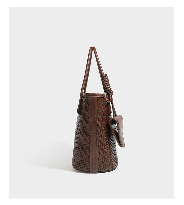 Structured woven-texture leather-look bucket bag in brown with knotted top handles, small front flap pouch, and adjustable