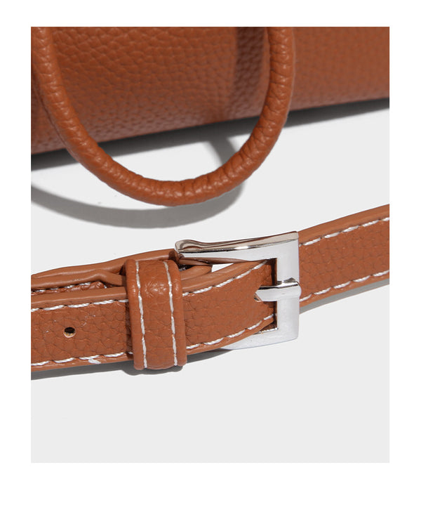 Small two-tone pebbled drawstring bucket bag with tan contrast base, metal toggle hardware, short top handle, and detachable