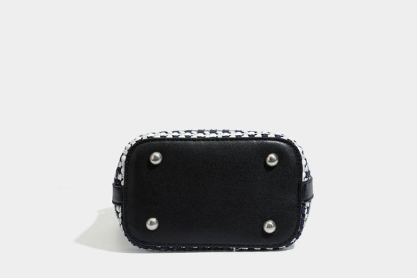 Small structured woven checker bucket bag with braided top handle, drawstring closure, and silver-tone hardware in black