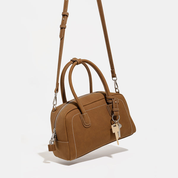 Kompakte, strukturierte Henkeltasche mit matter genarbter Oberfläche, geknoteten Doppelgriffen, goldenem Schlüsselanhänger und abnehmbarem, Detailansicht