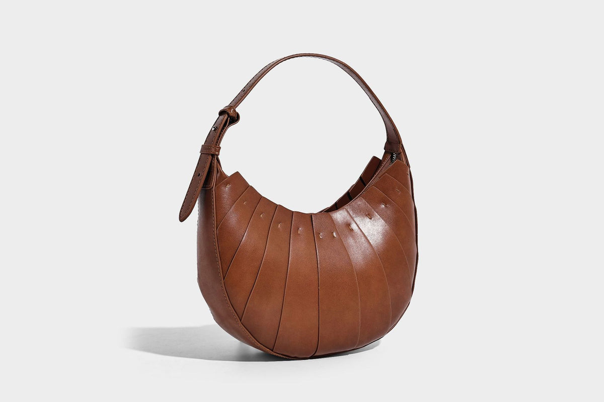 Crescent half-moon shoulder bag with vertical panel seaming, matte-satin leather-look finish, and adjustable gold-tone