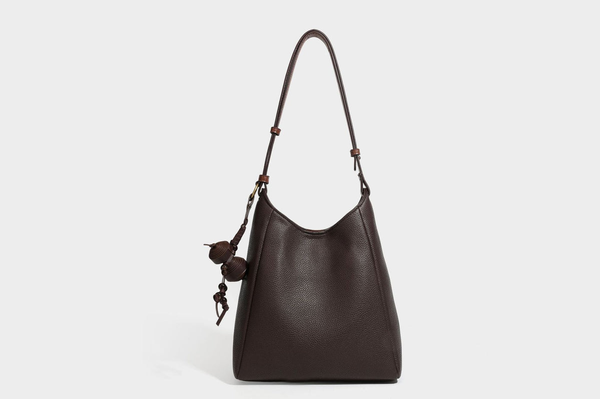 Hobo-Schultertasche in dunklem Espresso mit genarbter Oberfläche, warmen cognacfarbenen Details, verstellbarem schmalem Riemen, goldfarbenen Ringbeschlägen und geknotetem