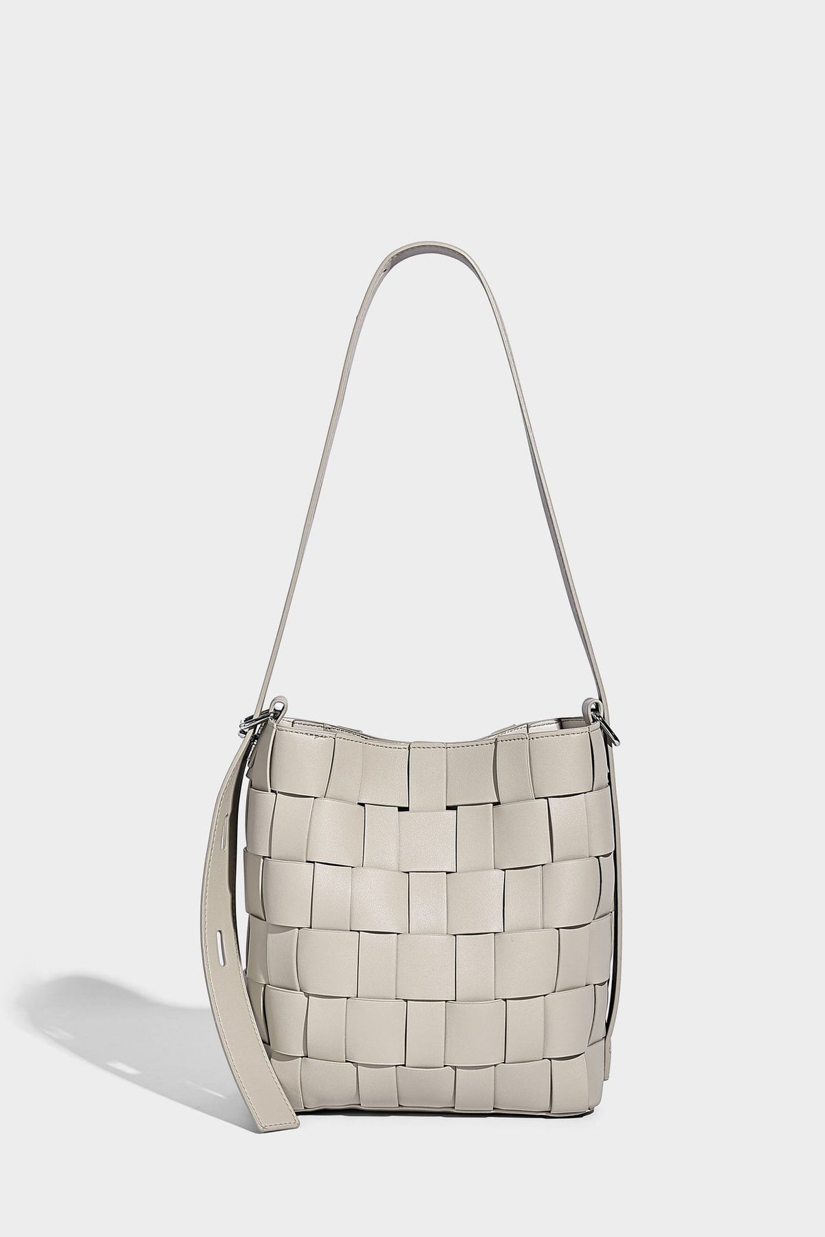 Hand-woven black-and-white checkerboard bucket bag with smooth black trim, silver-tone ring hardware, and adjustable