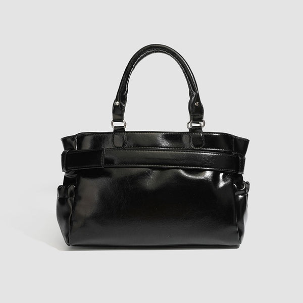 Black glossy structured tote bag with rivet and buckle detail, dual top handles, and detachable shoulder strap, detail view 5