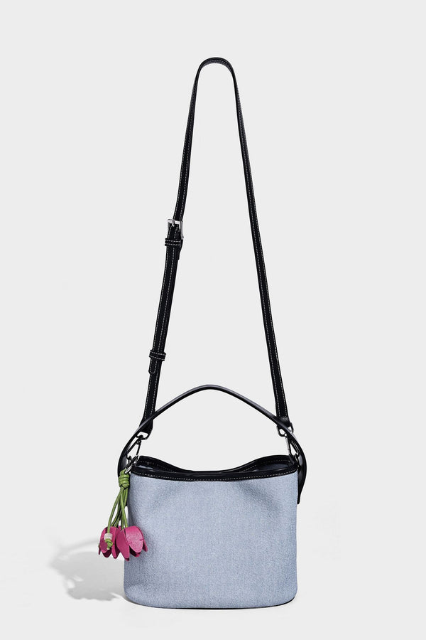 Hellblaue Bucket-Bag aus Denim mit schwarzem Besatz in Lederoptik, silberfarbenen Beschlägen, kurzem Tragegriff und langem verstellbarem Crossbody-Riemen