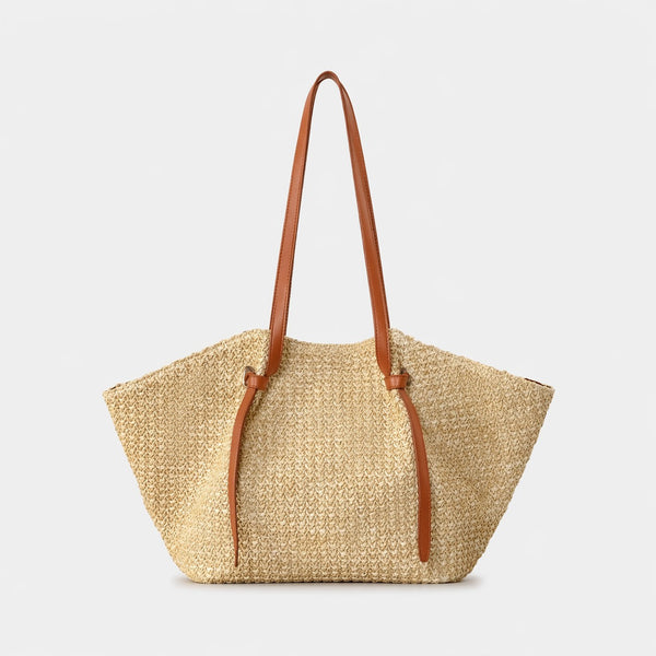 Große Tote-Bag aus geflochtenem Stroh mit Schulterriemen aus schwarzem Lederimitat und geknoteten Riemendetails, trapezförmiger Korpus in Natur-Tan