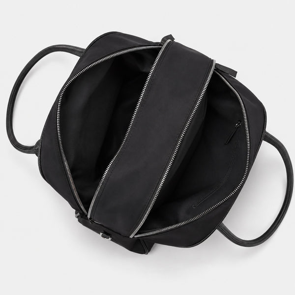 Structured dome top-handle bag in matte nylon with pebbled vegan leather-look trim, zip-top closure, front slip pocket, and