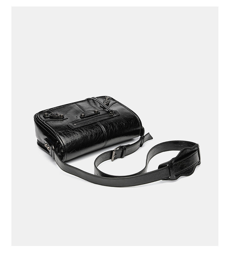Small structured rectangular crossbody bag with crinkle leather-look finish, front zip pocket, gunmetal stud hardware, and