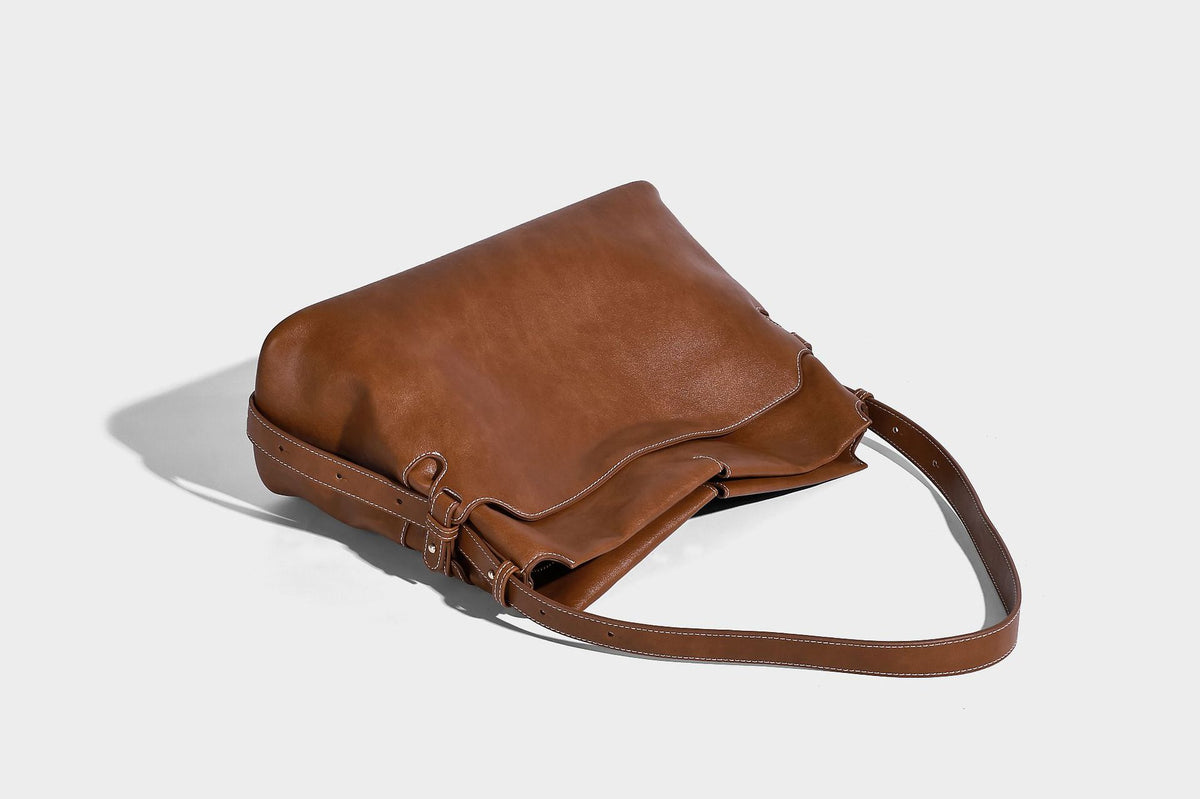 Large slouchy leather-look hobo tote bag with open top, adjustable shoulder strap, and colorful tassel bead charm, detail