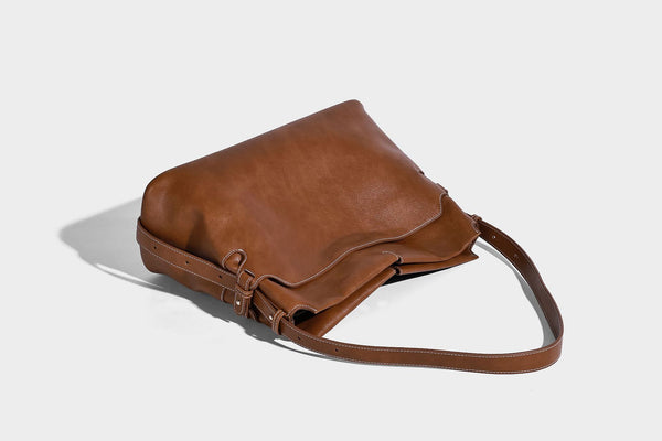 Large slouchy leather-look hobo tote bag with open top, adjustable shoulder strap, and colorful tassel bead charm, detail