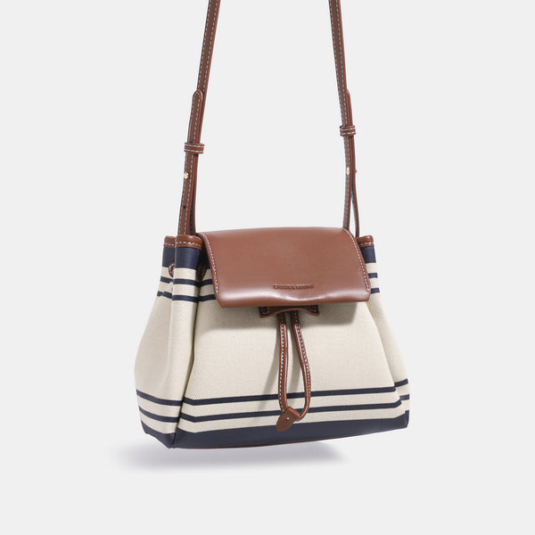 Cremefarbene Canvas-Beuteltasche mit marineblauen horizontalen Streifen, cognacfarbenem Kunstleder-Lappen und -Besatz, goldfarbenen Metalldetails und wandelbarer Trageweise