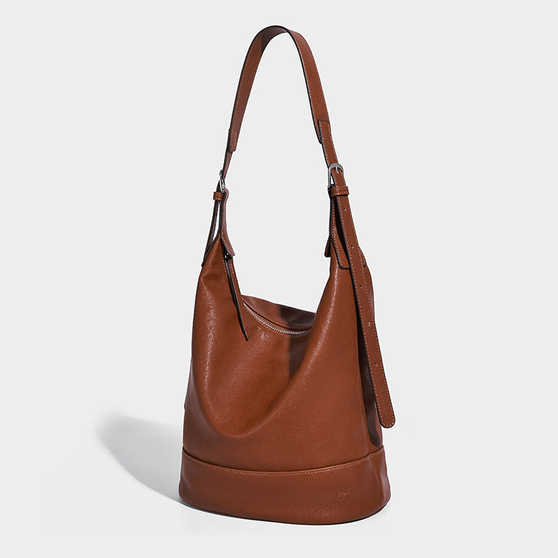 Slouchy bucket hobo shoulder bag in dark brown with glossy leather-look finish, top zip closure, and long adjustable, detail