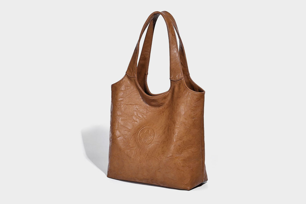 Large open-top tote bag with crinkled leather-look finish, long double shoulder straps, and embossed circular detail on