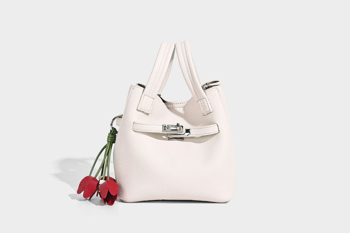 Small structured pebbled bucket tote bag with dual top handles, silver turn-lock front pocket, and detachable shoulder strap