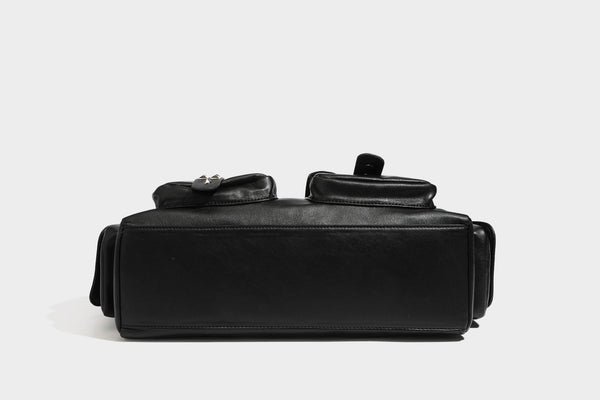 Black leather-look tote bag with silver pyramid studs on handles and front panel, multiple flap and zip exterior pockets