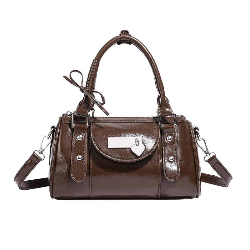 Kleine strukturierte Henkeltasche in glänzender Lederoptik mit Henkeln mit Schleifendetails und Vordertasche mit Herzverschluss, Detailansicht