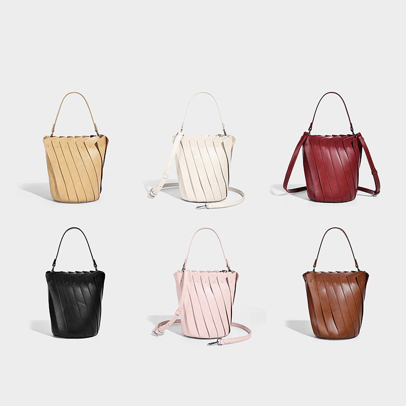 Structured pleated-panel bucket bag with curved top handle and detachable adjustable shoulder strap in smooth matte, detail