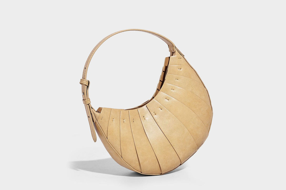Crescent half-moon shoulder bag with vertical panel seaming, matte-satin leather-look finish, and adjustable gold-tone