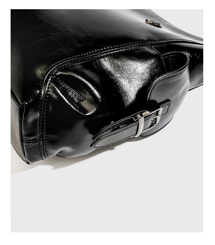 Slouchy hobo shoulder bag with glossy leather-look finish, silver-tone chain drape across front, side buckle pockets, and