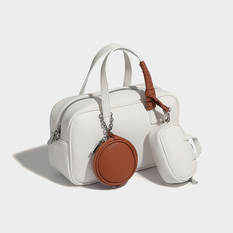 Structured pebbled leather-look Boston bowling bag in tan with blue detachable round mini pouch, dual top handles, and