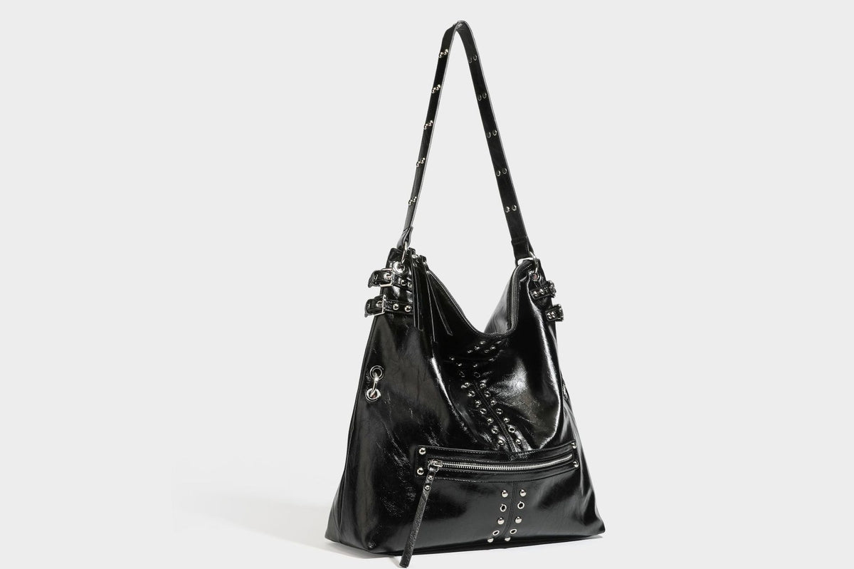 Black glossy leather-look slouchy shoulder bag with silver stud and eyelet hardware, top zip closure, front zip pocket, and