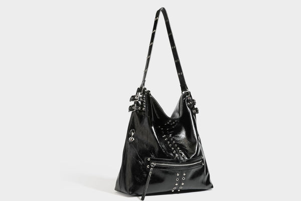 Black glossy leather-look slouchy shoulder bag with silver stud and eyelet hardware, top zip closure, front zip pocket, and