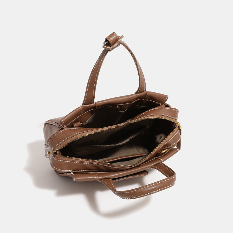 Compact structured satchel bag with dual top handles, gold-tone O-ring hardware, contrast topstitching, and detachable