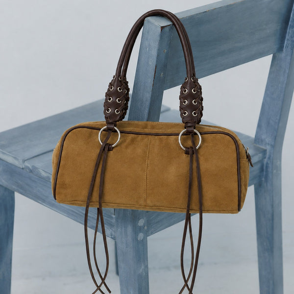 Rectangular suede-look barrel bag with laced eyelet handles, silver O-ring hardware, and hanging leather-look fringe tie